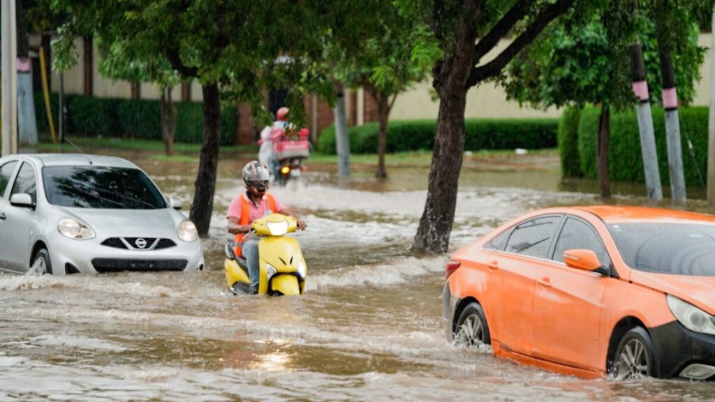 A group of people riding motorcycles through a flooded street